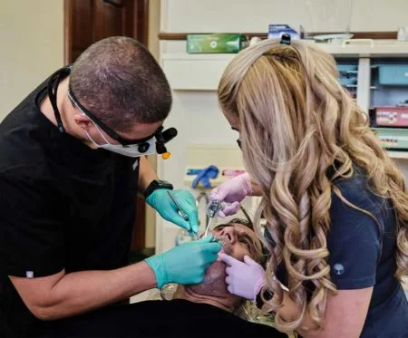 Dr. Gio of Flossy Smiles in Miami, FL working on a patient's teeth with his assistant
